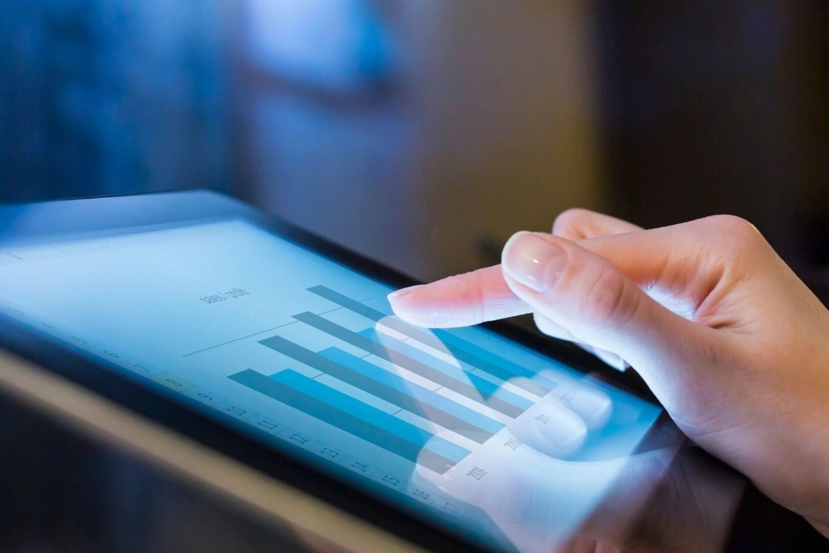 A person touching an ipad with a bar graph on it.